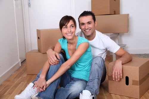 Professional movers loading household items into a van on a residential New Cross street